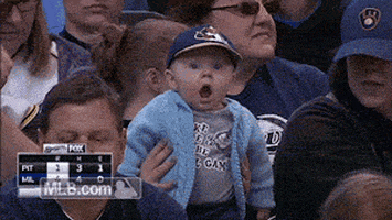 Sports gif. A baby is at a baseball game and they're being held on top of someone's legs. They stare out into the field wide eyed with their jaw dropped, and they're utterly shocked.