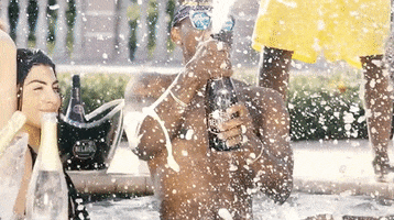 Ad gif. Man in a purple bandana headband and blue shades pops a Luc Belaire wine bottle in the pool, and it sprays wildly into the air, amplifying the carefree, summer vibe.