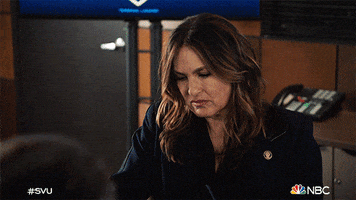 TV gif. Mariska Hargitay as Olivia in Law and Order SVU. She puts on her glasses to peer intently at her phone, opening her mouth in concentration.