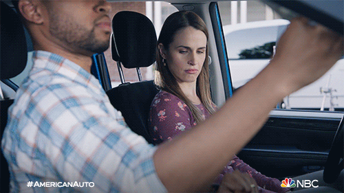 TV gif. Alexandra Siegel as Michelle and Tye White
 as Jack in American Auto. They're sitting in a car and Jack is driving. He tries to adjust his seat but is very awkward about it and ends up bouncing around in the driver's seat. Michelle gives him a confused face and watches him.
