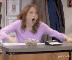 The Office gif. Ellie Kemper as Erin pops up from her seat and starts violently fist pumping the air and yelling out in immense excitement.