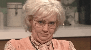 SNL gif. Kate Mckinnon, dressed as an old lady, looks straight into the camera with bedroom eyes. She gives a suggestive wink, and then a cheeky smile while raising her eyebrow flirtatiously. 