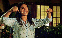 TV gif. Gina Rodriguez as Jane Villanueva in Jane the Virgin, pumps her fists in elated celebration, moonwalking away with tears of joy in her eyes.