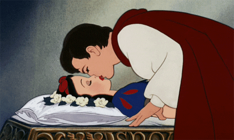 Disney gif. Prince Ferdinand in Snow White and the Seven Dwarfs kisses Snow White while she's asleep.