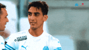 Video gif. Oussama Targhalline and Pol Lirola wear soccer jerseys as they hug each other offering congratulations.  