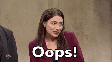 SNL gif. Actor Melissa Villasenor impersonating Alexandria Ocasio Cortez shrugs and puts her hands to her mouth with a mischievous smile. The text says, "Oops," but she doesn't seem to be very sorry at all. 