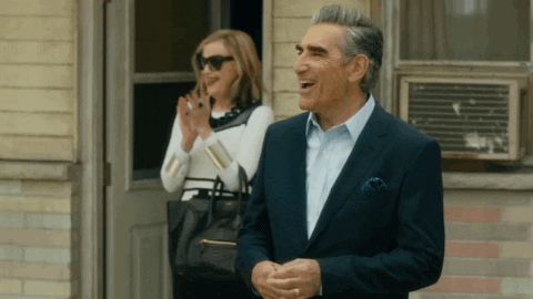 Schitt's Creek gif. Eugene Levy as Johnny standing outside with Catherine O'Hara as Moira smiling and applauding.