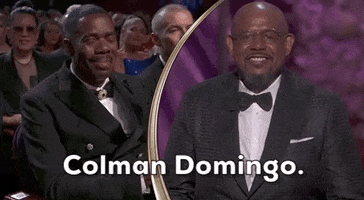 Oscars 2024 GIF. Forest Whitaker smiles before saying "Colman Domingo" and turning towards him. We see Domingo tearfully smiling back at Whitaker. 