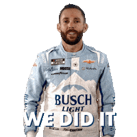 Sponsored sticker gif. NASCAR driver Ross Chastain smiles and holds his fist in the air in triumph. He wears a driver fire suit decorated with many sponsor logos with the largest being the Busch Light beer logo across the center of his abdomen. Text reads, “We did it.”