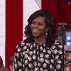 Video gif. At a rally or campaign event, First Lady Michelle Obama stands on a stage. She points her finger straight up into the air to emphasize something. Above her finger, the word "This!" appears in all caps.