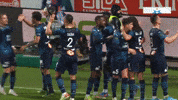 Sports gif. Ligue 1 club Marseille players congratulate each other on the field, hugging, patting each other on the back, fist-bumping, and shaking hands.
