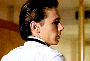 Celebrity gif. James Franco wears a tux as he turns to look over his shoulder and winks at us with a smile.