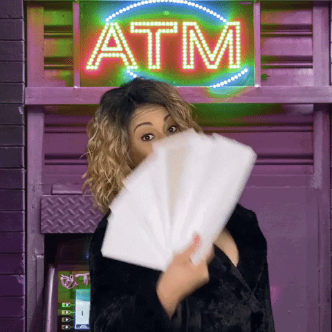 A woman fanning money in front of an ATM.
