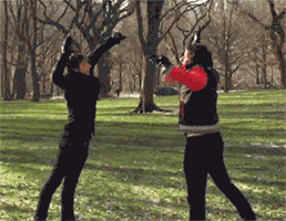 Video gif. Two men jump up, kicking both legs up, and high five.