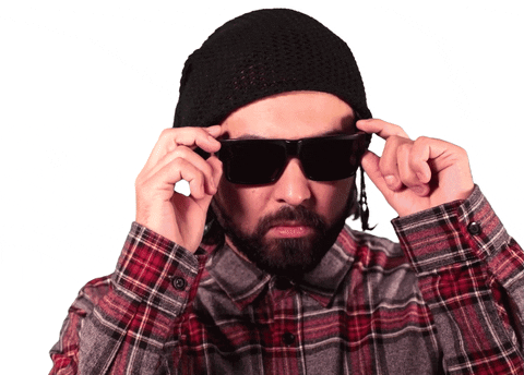 Video gif. Man lowers his sunglasses to show himself rolling his eyes.