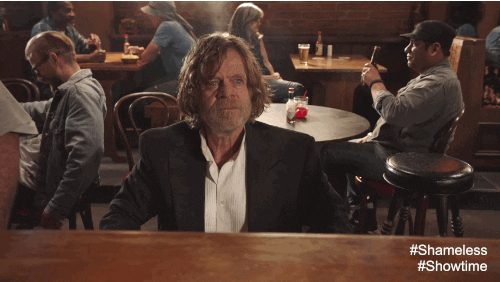 TV gif. William H Macy as Frank in Shameless sits at a bar and raises a firm pointed finger to something ahead of him. 