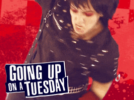 Video gif. Against a red checkered background with paint splatters, someone cosplaying as a heavy metal rockstar dressed in all black viciously punches at the ground, slams down their electric guitar, and tries kicking us in the face. However, they exert so much power that their goth wig falls off and reveals their bald cap. Text at the bottom reads, "Going up on a Tuesday."