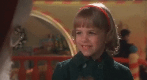 Movie gif. Samantha Krieger as Sami in Miracle on 34th Street. Sami is deaf and sits on Santa's lap and signs, "Thank you," to him with a joyous expression on her face.