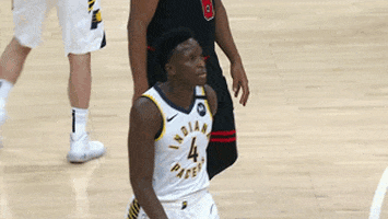 Sports gif. Victor Oladipo from the Indiana Pacers puts his hands into a heart symbol as he walks on the court.