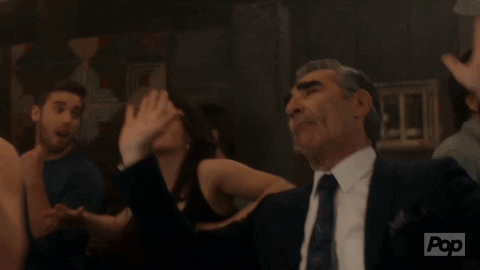 Schitt's Creek gif. Eugene Levy as Johnny presses his palms upward to raise the roof as he tilts his head back and closes his eye contentedly.