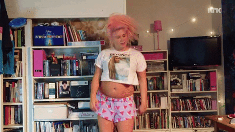 TV gif. With her pink hair in a high ponytail, Line of Line dater Norge dances happily while wearing a cut-off Beyonce shirt.