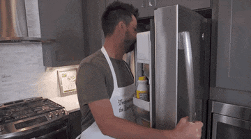 Celebrity gif. John Crist pulls a head of iceberg lettuce from a fridge, raises his hand in praise and then says "lettuce pray" which appears as text.