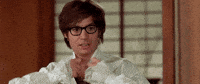 Movie gif. Gazing seductively, Mike Myers as Austin Powers rips open his shirt to reveal a very hairy chest.