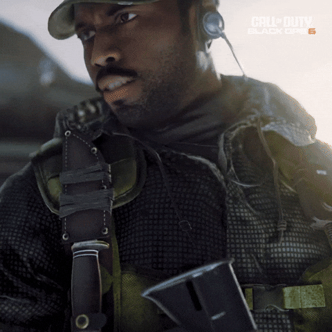 Sponsored gif. Man in combat gear slowly turns to look at a military helicopter where people are boarding.