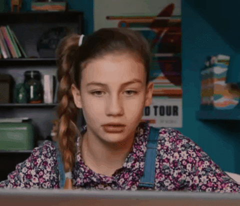 A girl giggles as she look at the screen of her laptop.