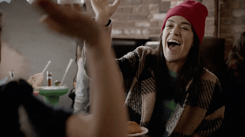 TV gif. Ilana Glazer and Abbi Jacobson in Broad City. They're sitting at lunch and are extremely pleased with themselves as they do a high five of pride.