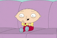Cartoon gif. Stewie from Family Guy sits on a couch and excitedly shakes his hands and legs. 