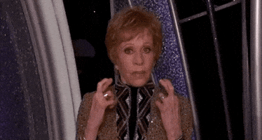 Celebrity gif. Carol Burnett at the Golden Globes appears on stage, staring at us intently and crossing her fingers in hopeful anticipation.