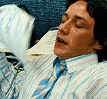 Celebrity gif. James McAvoy leans back in an office chair, face glistening with sweat. He breathes in and out heavily, fanning himself with papers. 