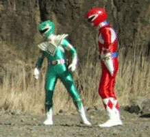 TV gif. Red Ranger and the Green Ranger on Mighty Morphin Power Rangers look at each other and shrug with the show's usual rocky battlefields in the background.