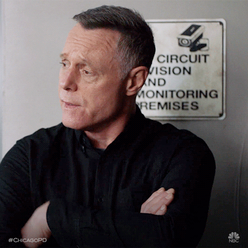 TV gif. Jason Beghe as Hank Voight on Chicago PD folds his arms and looks around nervously, biting his cheek.