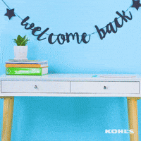 Video gif. A girl slides backwards in a desk chair and plops a folder on her desk. She props one foot up on the chair, folds her arms, and looks at the camera as she poses. There’s a banner above the desk that says, “Welcome back.”