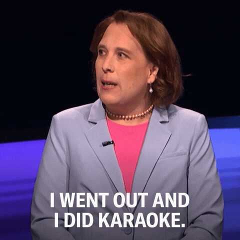 A picture of a woman in a pink undershirt and light jacket with a beaded neckless moving her mouth with the words "I went out and I did karaoke" right below.