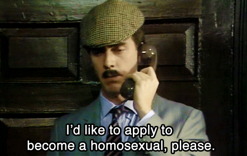 TV gif. From A Bit of Fry and Laurie, Hugh Laurie, dressed in a suit and newsboy cap with a tiny mustache, speaks into a telephone, saying, "I'd like to apply to become a homosexual, please," which appears as text.