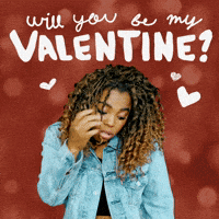 Video gif. A woman looks at us with a shy, awkward, one-corner smile as she runs tucks her curly hair behind her ear. Text, "Will you be my Valentine?"