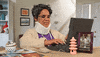 Video gif. Elderly woman has a neck brace on and she slowly types away at an antiquated laptop. She moves slowly as she types and squints her eyes at the screen.