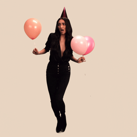 Celebrity gif. Shay Mitchell as a birthday hat on and holds balloons as she dances in celebration.