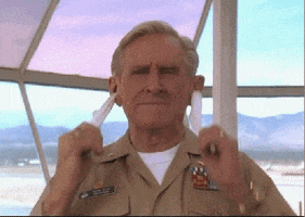 Movie gif. A proud-looking Lloyd Bridges as Admiral Benson in Hot Shots sees no issue with cleaning his ears by pulling a cloth all the way through his head.
