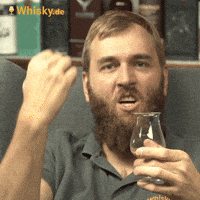 Video gif. Ben Luening from Whisky dot DE, holding a small whiskey glass, brings down his fist like he just won a bet. 