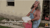 TV gif. An older man from Swamp People with long gray hair, wearing shirtless overalls and an American flag bandanna carries a red cooler out of a house. He speaks to us with a vague frown. Text, "It's gonna be another long day."