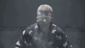 Music video gif. Danny Case from Ashes to New in the Hate Me Too music video. He's wearing a Hawaiian shirt and he's covered in white powder and he pounds his chest, making the smoke billow around him.