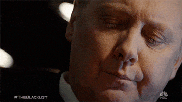 TV gif. James Spader as Red on the Blacklist. He's looking down but slowly flicks his eyes up as he judges, staring us down with a look of anger and disapproval on his face.