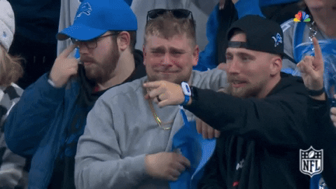 Sports gif. Slow motion video clip of a man in the stands at an NFL football game looking overcome with emotion, raising his baseball cap in the air and yelling through what look like uncontrollable tears of joy or relief.