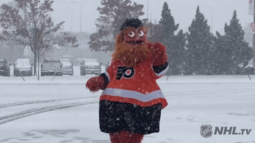 Sports gif. Gritty, the Philly Flyer mascot, jumps around in a snowy parking lot, trying to catch snowflakes and checking his hands to see if he caught any.