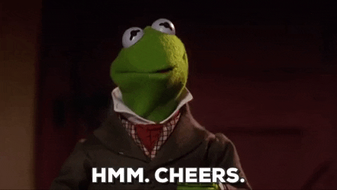 Muppets gif. Kermit, wearing a trench coat and a collared shirt, nods amiably and raises his cup. Text, "Hmm. Cheers."