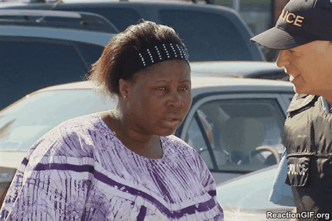 Video gif. Police officer speaks firmly to a woman in a purple tie-dye shirt, who appears dazed and confused before widening her eyes and mouth in slight shock.